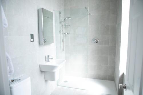 a white bathroom with a sink and a shower at The Royal Duchy Hotel in Falmouth