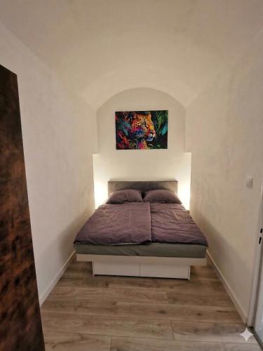 a bedroom with a bed with a painting on the wall at Alma Apartment DOWNTOWN in Košice