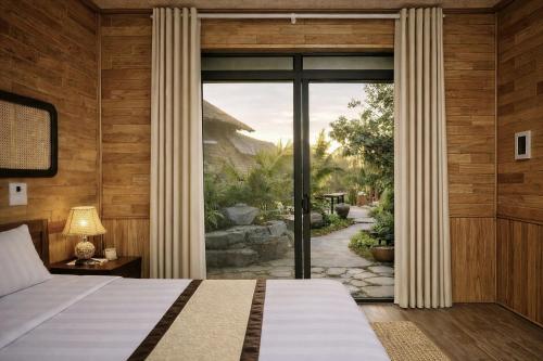 a bedroom with a bed and a large window at Hidden Valley Eco Retreat Trang An in Ninh Binh