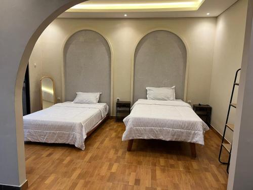 two beds in a room with two arched windows at Defano Villa Klotok in Yogyakarta