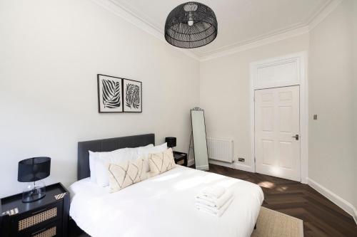 a bedroom with a white bed with a black headboard at JOIVY Family Flat near Leith in Edinburgh