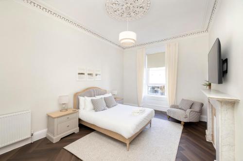a white bedroom with a bed and a chair at JOIVY Family Flat near Leith in Edinburgh