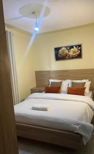 a bedroom with a large bed with a light on the ceiling at Noble Park Apartments in Kiserian