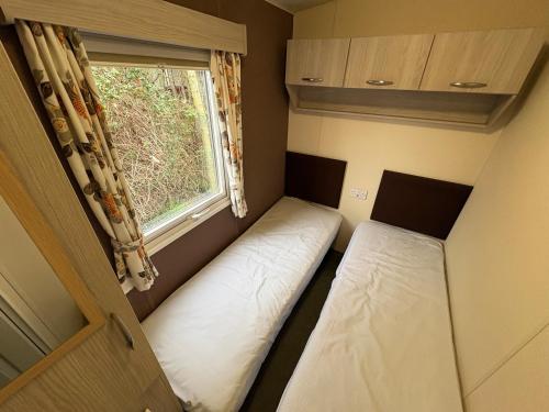 two beds in a small room with a window at Caravan 607 in Clacton-on-Sea