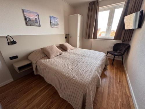 a bedroom with a bed and a chair in it at Appartementen Zeezicht - 3 in Katwijk aan Zee