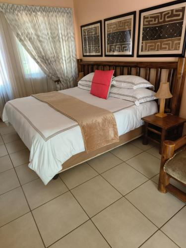 a bedroom with a large bed with a red pillow at Lalakamnandi Guesthouse in Pretoria
