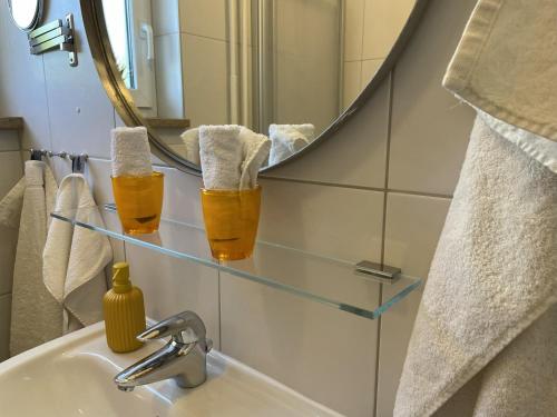 two glasses of beer on a bathroom sink in front of a mirror at FeWo Pelkmann - Die Grüne Oase - Ganzes Haus in Weikersheim