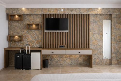 a room with two suitcases and a tv on a wall at Gokyuzu Hotel in Edremit