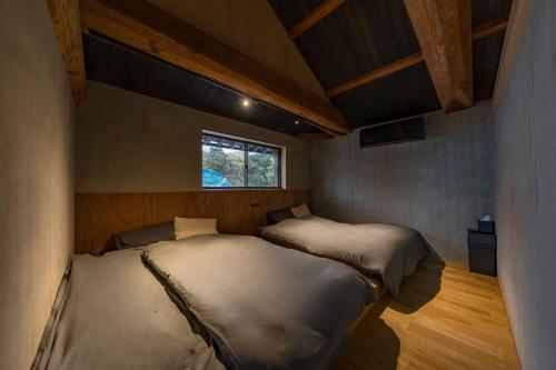 two beds in a small room with a window at Nui in Minamiawaji