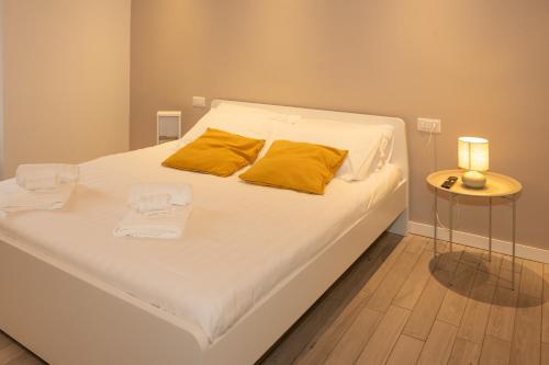 a white bed with yellow pillows and a side table at Dimora del Borgo in Lovere