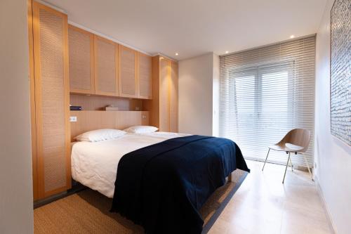 a bedroom with a bed and a chair and a window at Villa Castelli 52 Groenendijk in Nieuwpoort