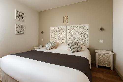 a bedroom with a large white bed with two pillows at Logis Hôtel Les Grenadines in Cap d'Agde