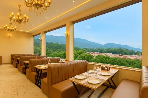a restaurant with tables and chairs and large windows at Hotel Nirvana Palace Near Parmarth Niketan in Rishīkesh