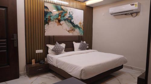 a bedroom with a bed with a painting on the wall at Hotel Golden Aura Inn in Gwalior