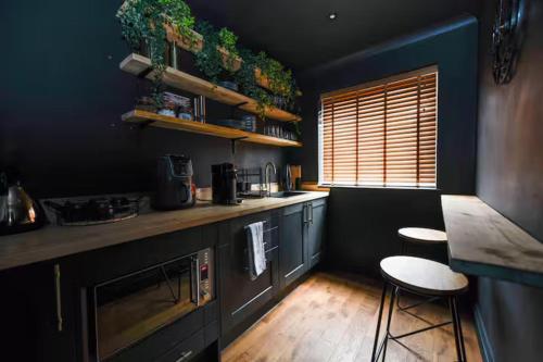 a kitchen with a counter and two stools in it at Bold Coastal Retreat with Boudoir Interiors, Felpham Village in Bognor Regis
