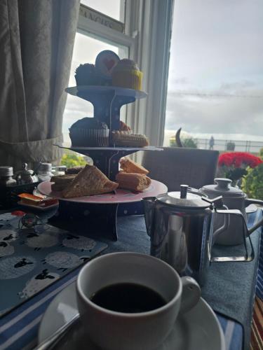 a table with a cup of coffee and a plate of food at St. Hilary Guest House in Llandudno