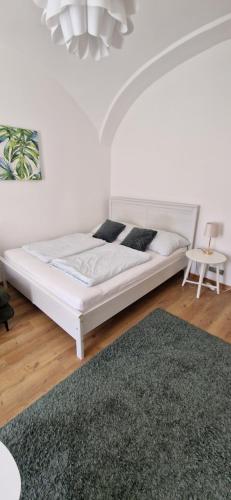 a white bed in a white room with a rug at GOLD 3 in Sopron