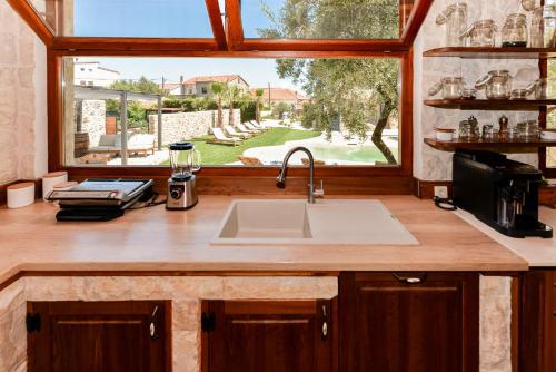 a kitchen with a sink and a large window at Magna in Dobropoljana
