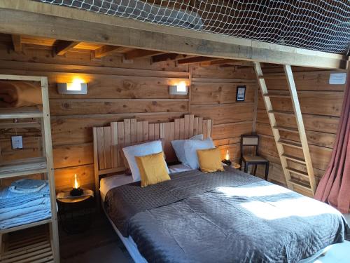 a bedroom with a bed in a wooden cabin at Domaine du Der - au milieu de nulle part, Chambres et tables dhotes au lac du Der in Outines
