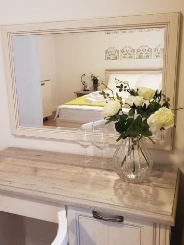 a vase of flowers on a table in front of a mirror at Stabu Sēta Residence in Riga