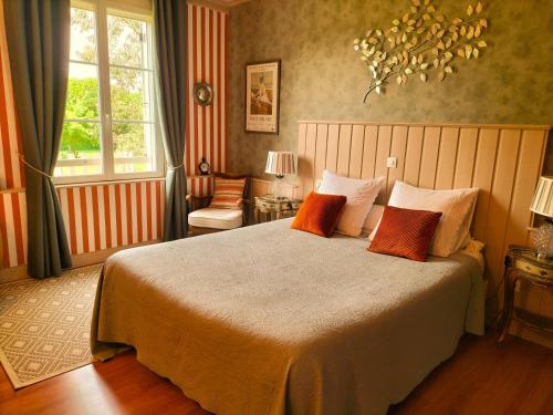 a bedroom with a large bed with orange pillows at Le Clos Lauradière in Cormeilles