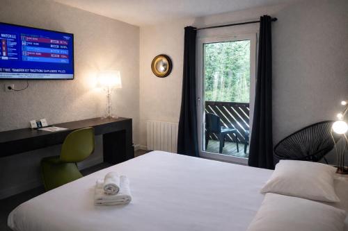 a hotel room with a bed and a desk and a window at Enzo Hôtels Diane - Logis Amnéville in Amnéville