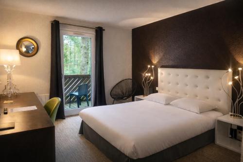 a bedroom with a bed and a window and a desk at Enzo Hôtels Diane - Logis Amnéville in Amnéville