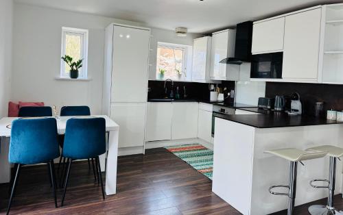 a kitchen with white cabinets and blue chairs at London Excel O2 Arena - Apartment with River view in London