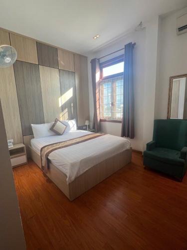 a bedroom with a bed and a green chair at Phi Long Hotel in Tuy Hoa
