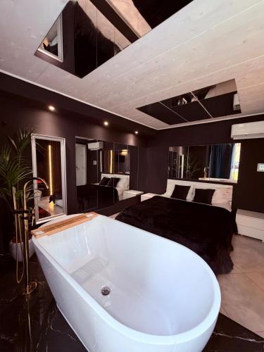 a large bathroom with a bath tub in front of a bed at Ama Suite Romantic Spa in Bologna