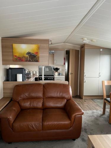 a living room with a brown leather couch and a kitchen at Maneight Retreat with Hot tub in New Cumnock