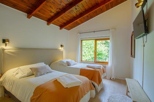 two beds in a room with a window at Hostería Carelhue in San Carlos de Bariloche