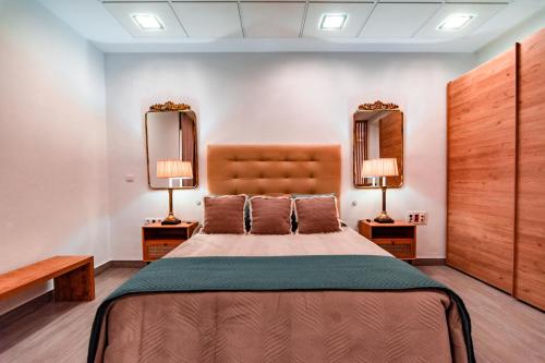 a bedroom with a large bed and two mirrors at EDomus Medellin 1485 Suites in Don Benito
