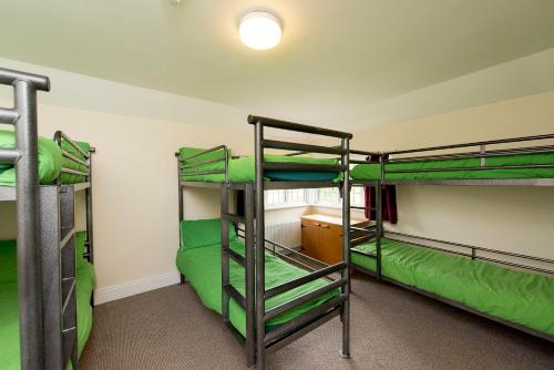 three bunk beds in a room with green sheets at Secluded Seven Room House in Okehampton