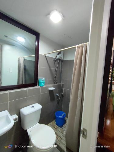 a bathroom with a toilet and a sink and a mirror at Sugarland Urban Nook in Bacolod