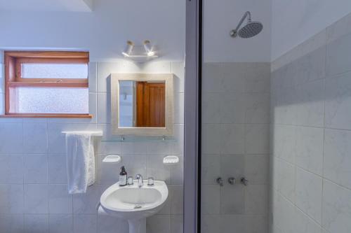 a white bathroom with a sink and a shower at Hostería Carelhue in San Carlos de Bariloche