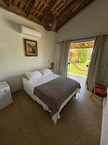 a bedroom with a bed and a large window at Casa Pathuá Corumbau in Corumbau
