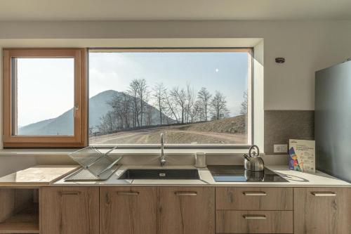 a kitchen with a sink and a large window at Nest Love, Bedollo Ospitar in Bedollo