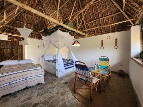 a bedroom with two beds and a table and chairs at Lemara Eco Camp in Kisaki