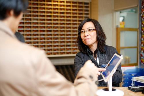 a woman sitting at a table talking to a man at Shinjuku Kuyakusho-mae Capsule Hotel in Tokyo