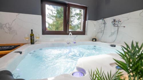 a large bath tub with a bottle of wine and a window at Casa Foresta by Villas Guide in Mrkopalj