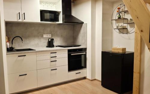 a kitchen with white cabinets and a black refrigerator at Palác Apartment in Strakonice
