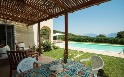 a patio with a table and chairs and a pool at Villa Harmony in Karavomylos
