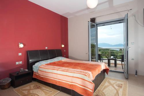 a bedroom with red walls and a bed and a balcony at Villa Harmony in Karavomylos