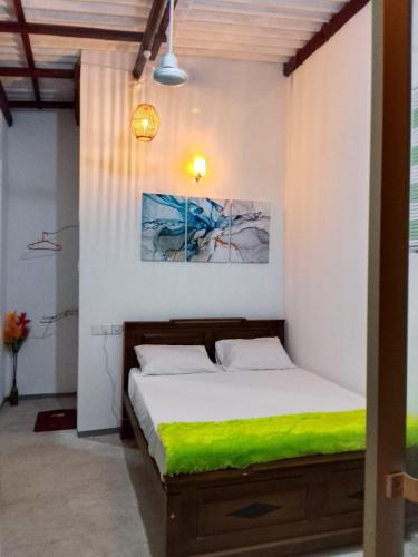 a bedroom with a bed with a green blanket at Sun Beach Villa in Weligama