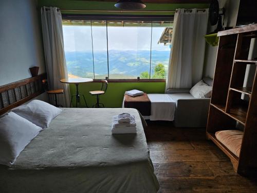a room with two beds and a large window at Chales Quinteto de Cores in Lavras Novas