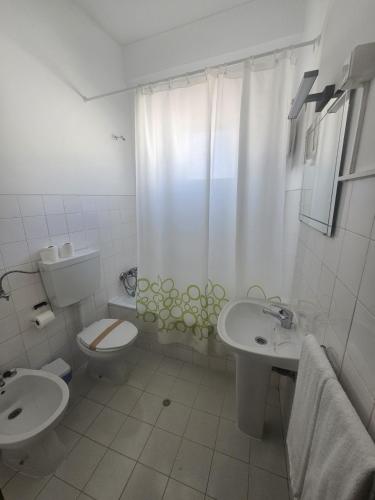 a white bathroom with a toilet and a sink at Romeu in Quarteira