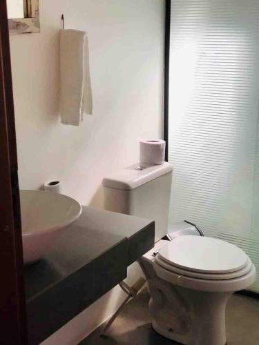 a bathroom with a white toilet and a sink at Casa Morro da Borússia in Osório
