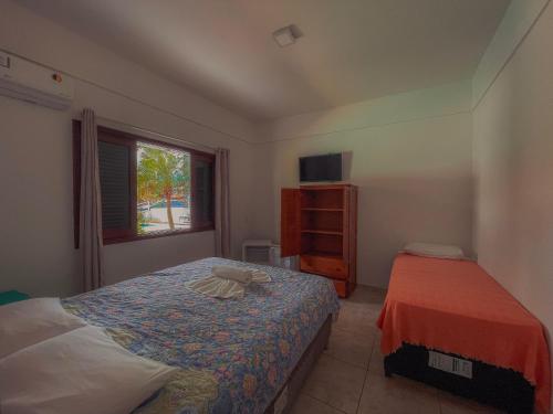 a bedroom with a bed and a dresser and a window at Pousada Acquaville PISCINA CLIMATIZADA in Bertioga