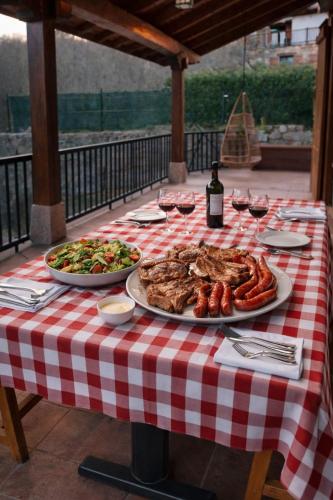 a red and white checkered table with food and wine at El eco de los robles in Sumbilla
